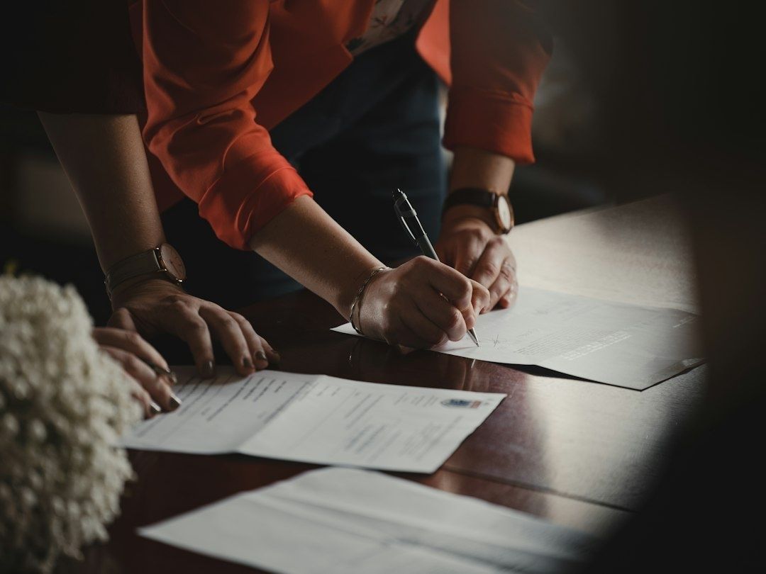 People reviewing and signing financial paperwork at a table